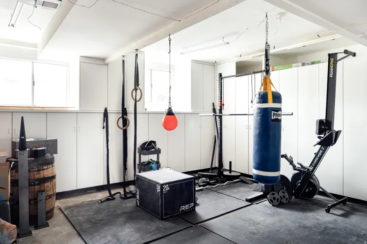 Two car garage with extended space in the back featuring white built-in cabinetry, concrete flooring with rubber matting, and recessed lighting