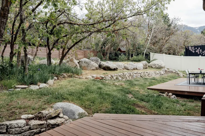 Tiered landscape featuring natural boulders, stone retaining walls, and mature trees
