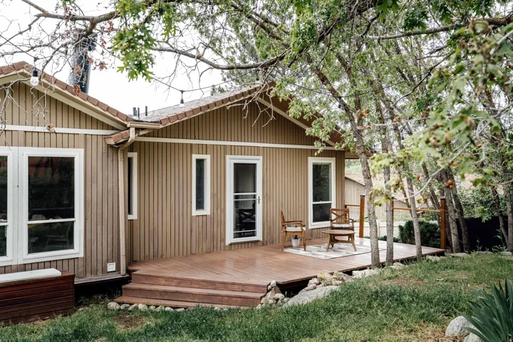 Exterior featuring horizontal siding, a multi-level wood-finish deck with railing, white window trim, and a screen door