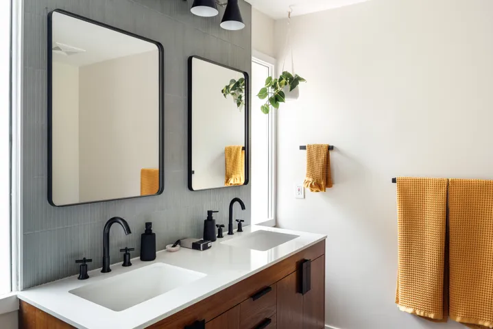 Dual rectangular framed mirrors above a wood-finish vanity with a white countertop and integrated sinks