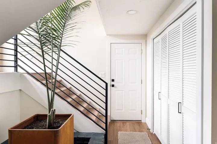 Entryway featuring wood-finish flooring, a white paneled door with matte black hardware, and louvered bifold closet doors