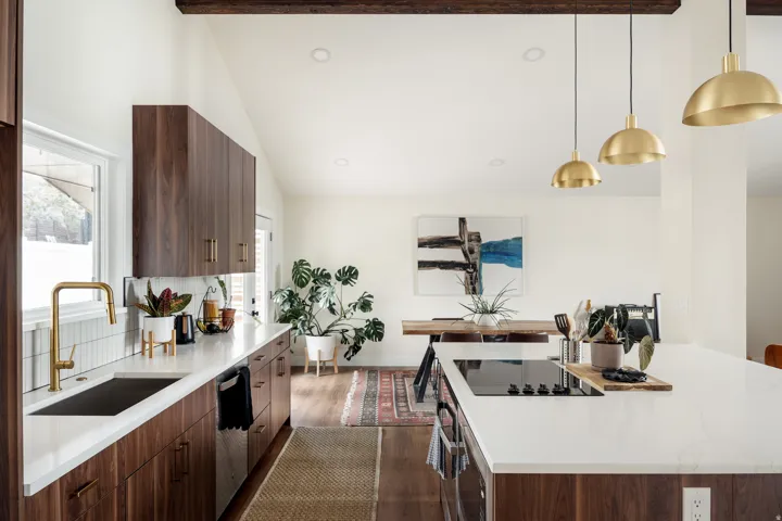 Modern kitchen featuring warm wood-finish cabinetry, bright white countertops, and a white subway tile backsplash