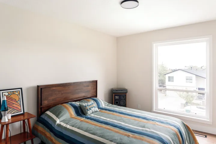 Bright room featuring a large window with white trim, light-toned wall paint, and a contemporary ceiling light fixture