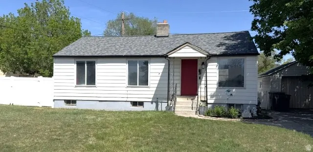 Single-story residence featuring white siding, a contrasting red entry door, and a gray shingle roof