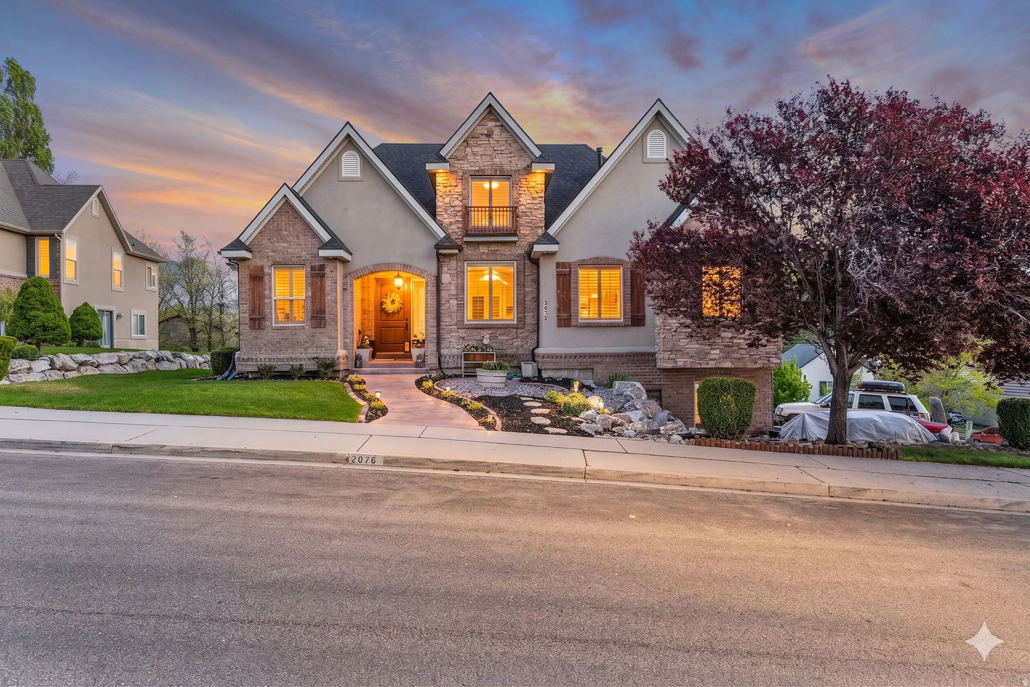 Stately stucco and stone facade residence featuring multiple gables and a covered arched entryway