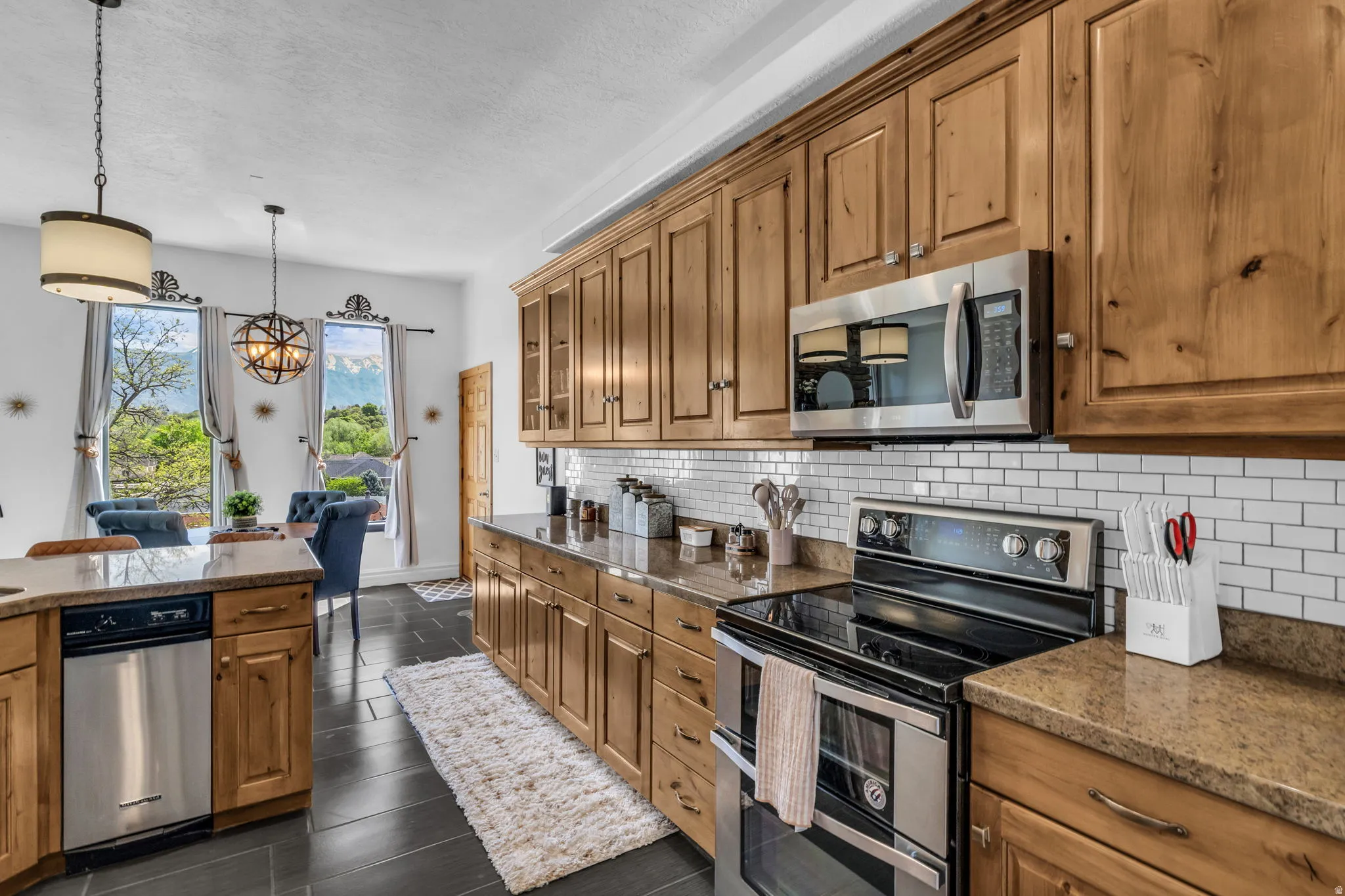 Kitchen featuring wood cabinetry, stainless steel appliances, subway tile backsplash, and dark tile flooring