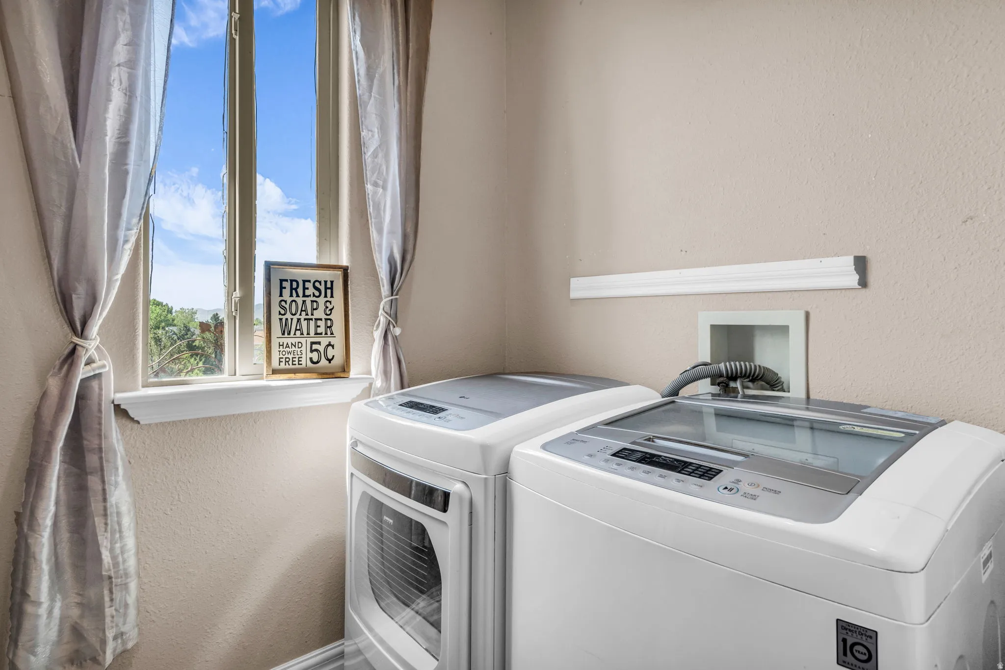Laundry area featuring a window, textured walls, and provisions for appliances