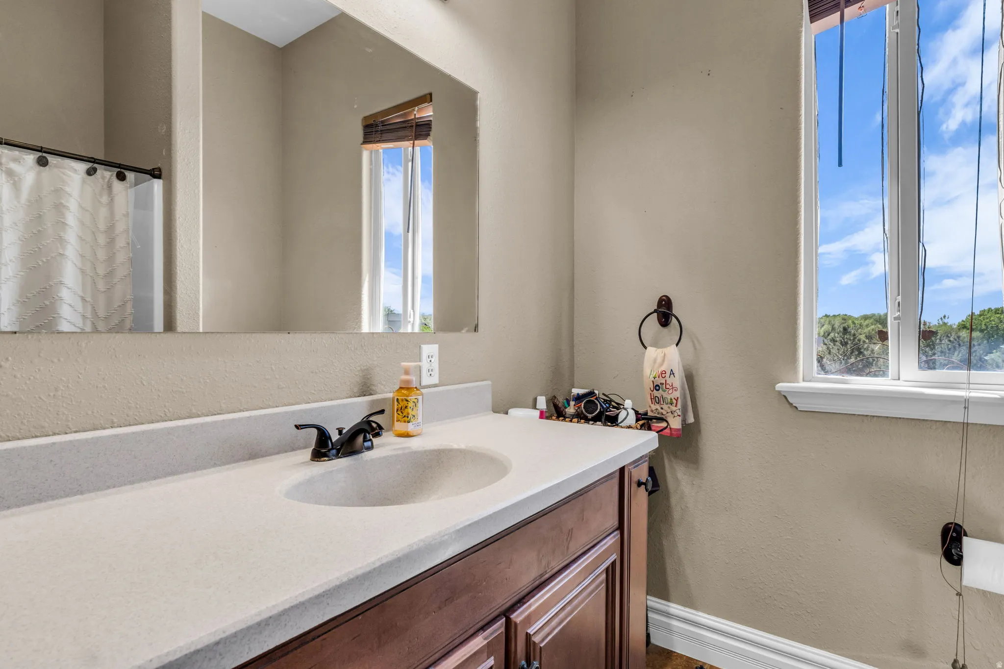 Bathroom vanity with a light-toned countertop, integrated sink, and dark bronze-finish faucet
