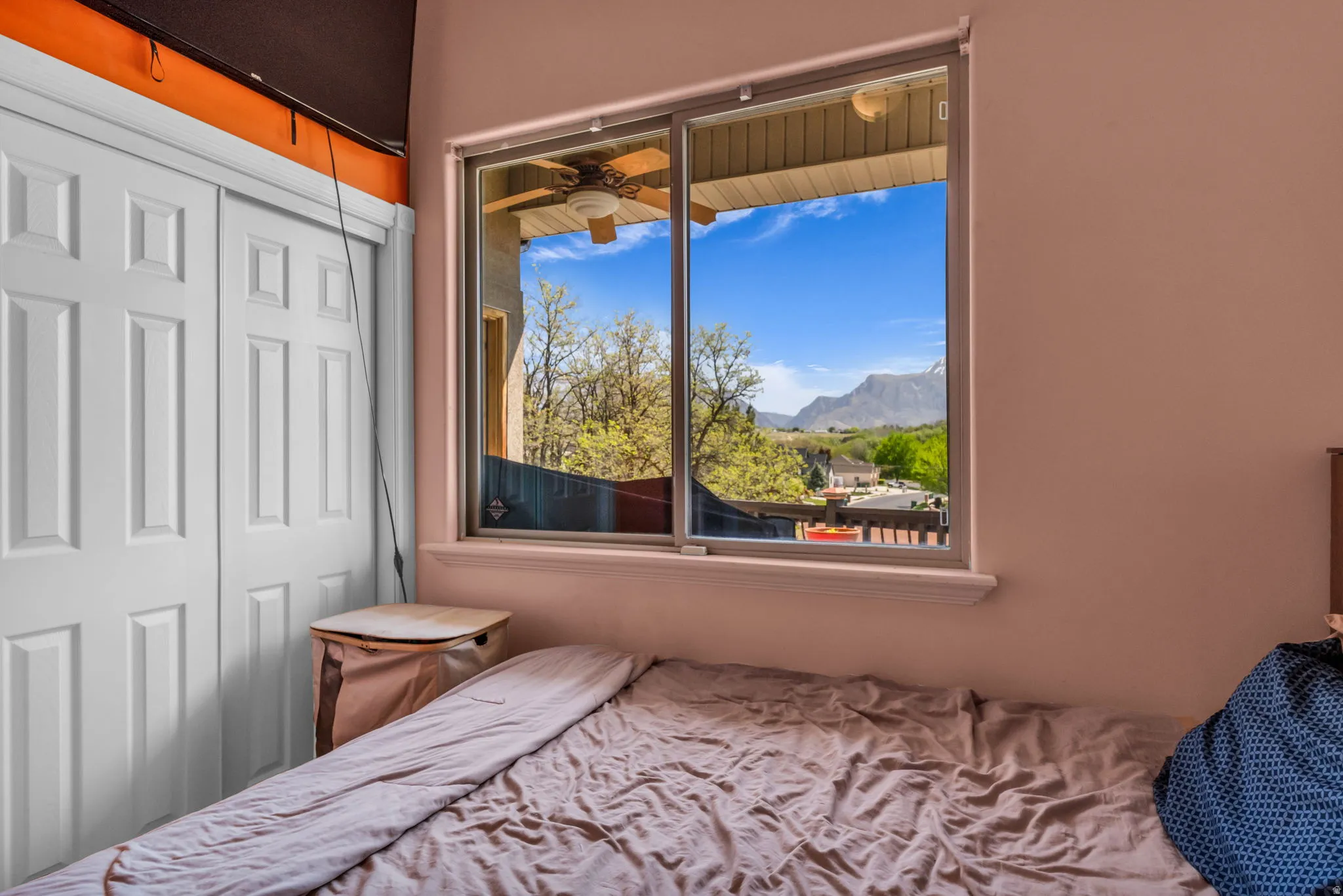 Window framing a mountain landscape, showcasing a ceiling fan on an exterior balcony