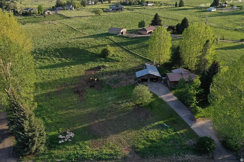Expansive property featuring a main residence with a brown roof, an adjacent outbuilding with a metal roof, and a paved driveway