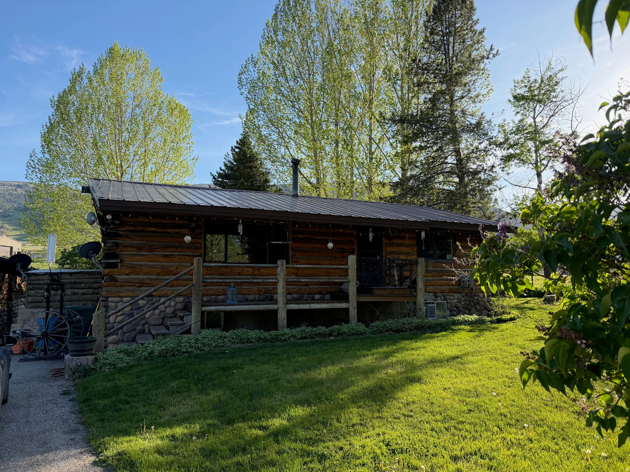 Log cabin exterior featuring a dark metal roof, stone foundation, and a covered porch