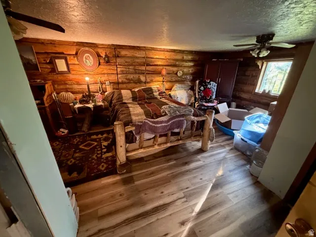 Wood-finish flooring throughout, complemented by log-style walls and a ceiling fan