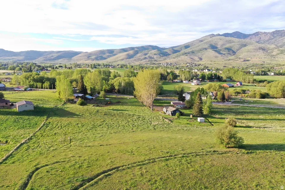 Expansive green fields with distant mountains and scattered residential structures