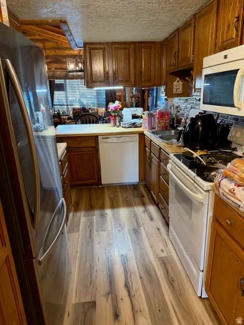 Kitchen featuring wood-finish flooring, oak cabinetry, and a tile backsplash