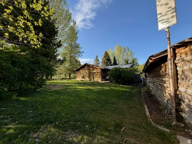 Rustic log structures set amidst a spacious grassy area with mature trees