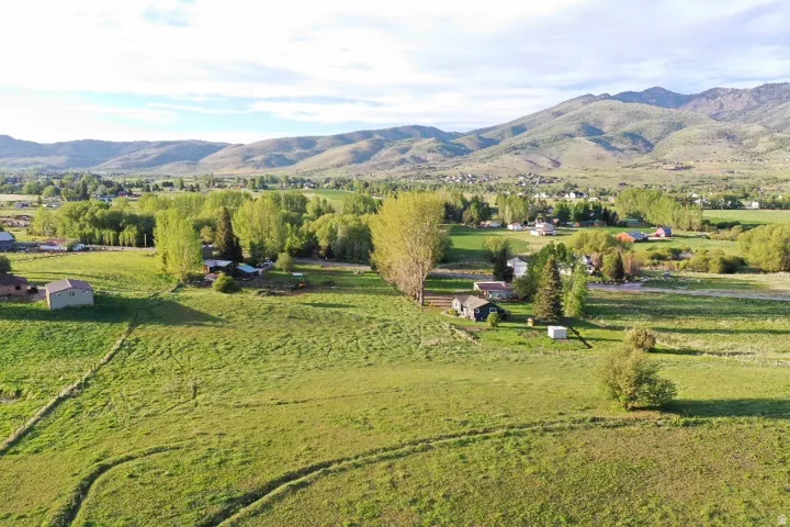 Expansive green fields with distant mountains and scattered residential structures
