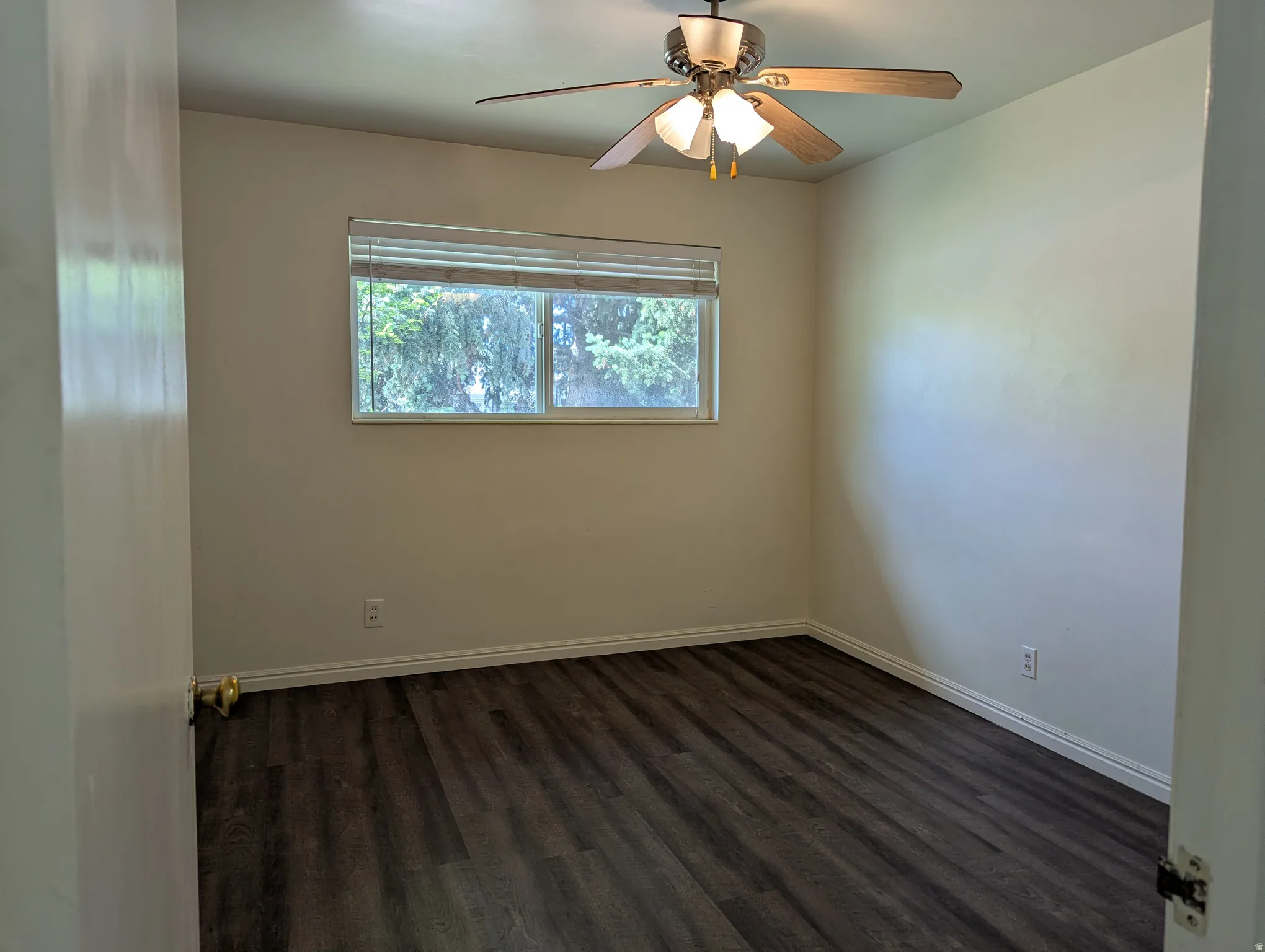 Bedroom 1 featuring laminate wood-finish flooring, neutral wall paint, and white baseboards