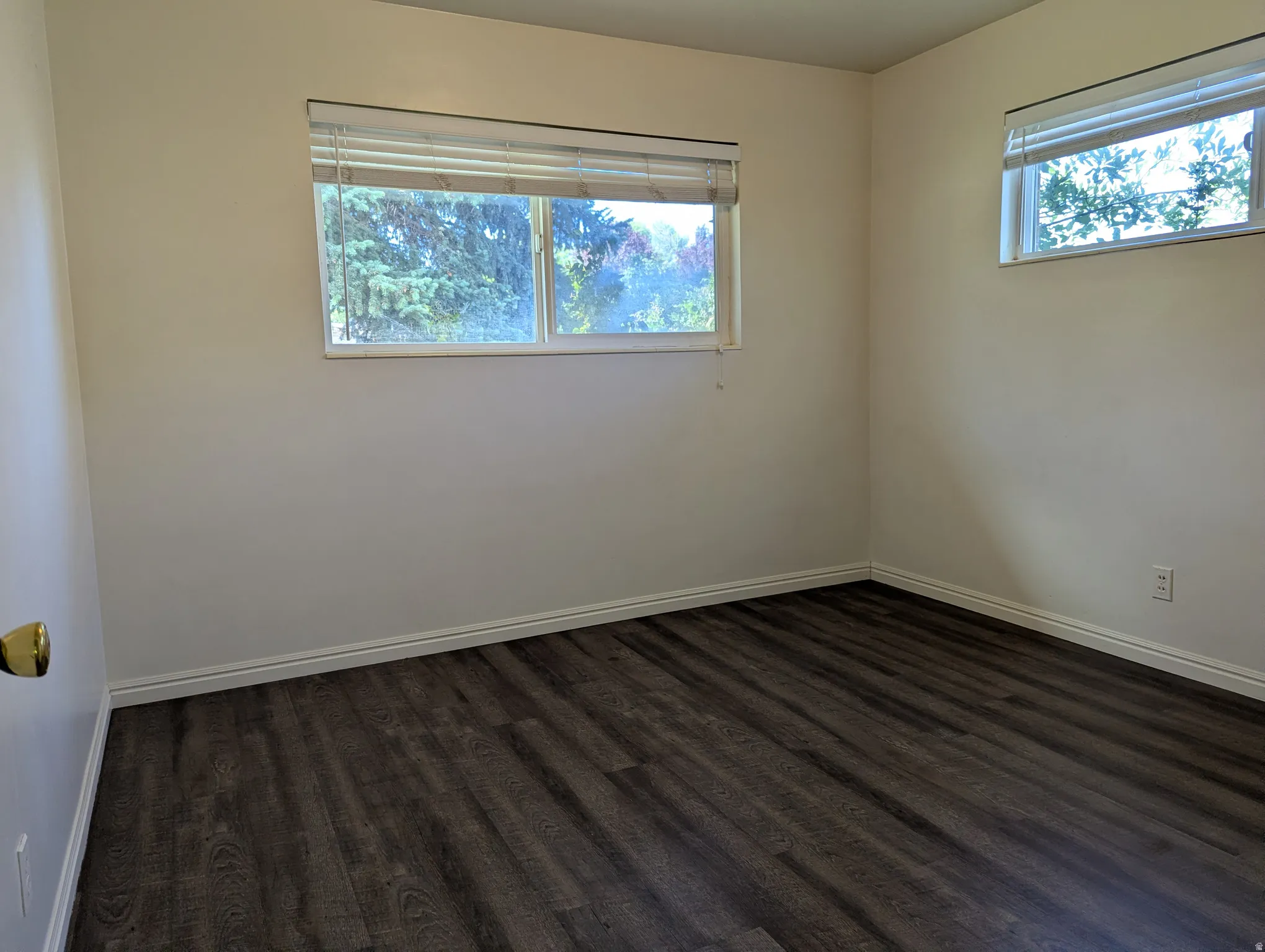 Bedroom 3 featuring laminate wood-finish flooring, white baseboards, and two windows with white blinds