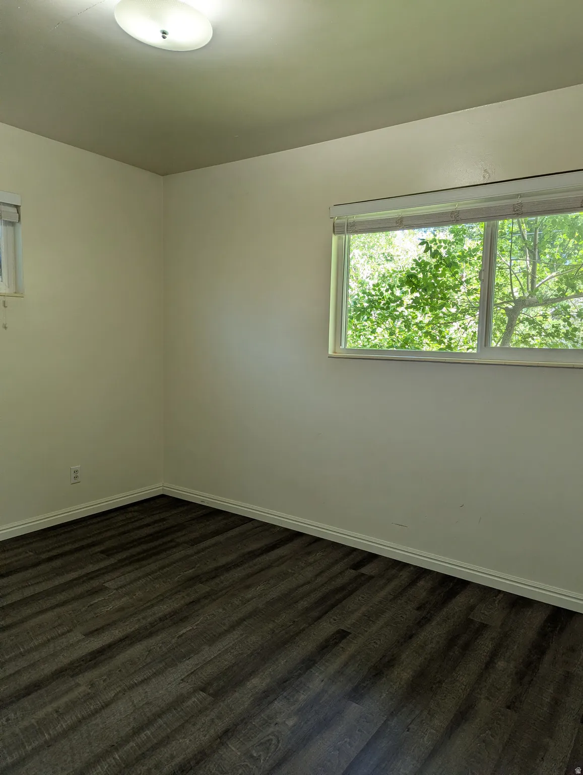 Bedroom 2 featuring laminate wood-finish flooring, light-toned walls, and white baseboards