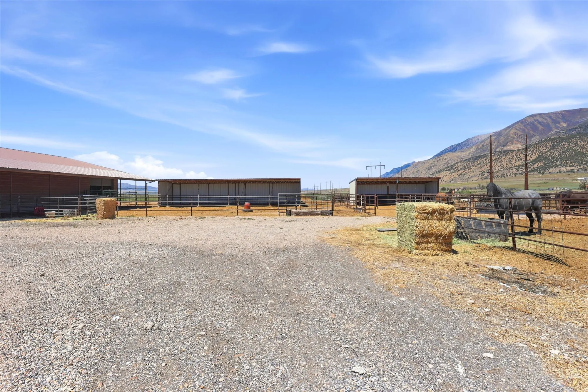 Expansive gravel lot featuring two large covered structures and extensive metal fencing