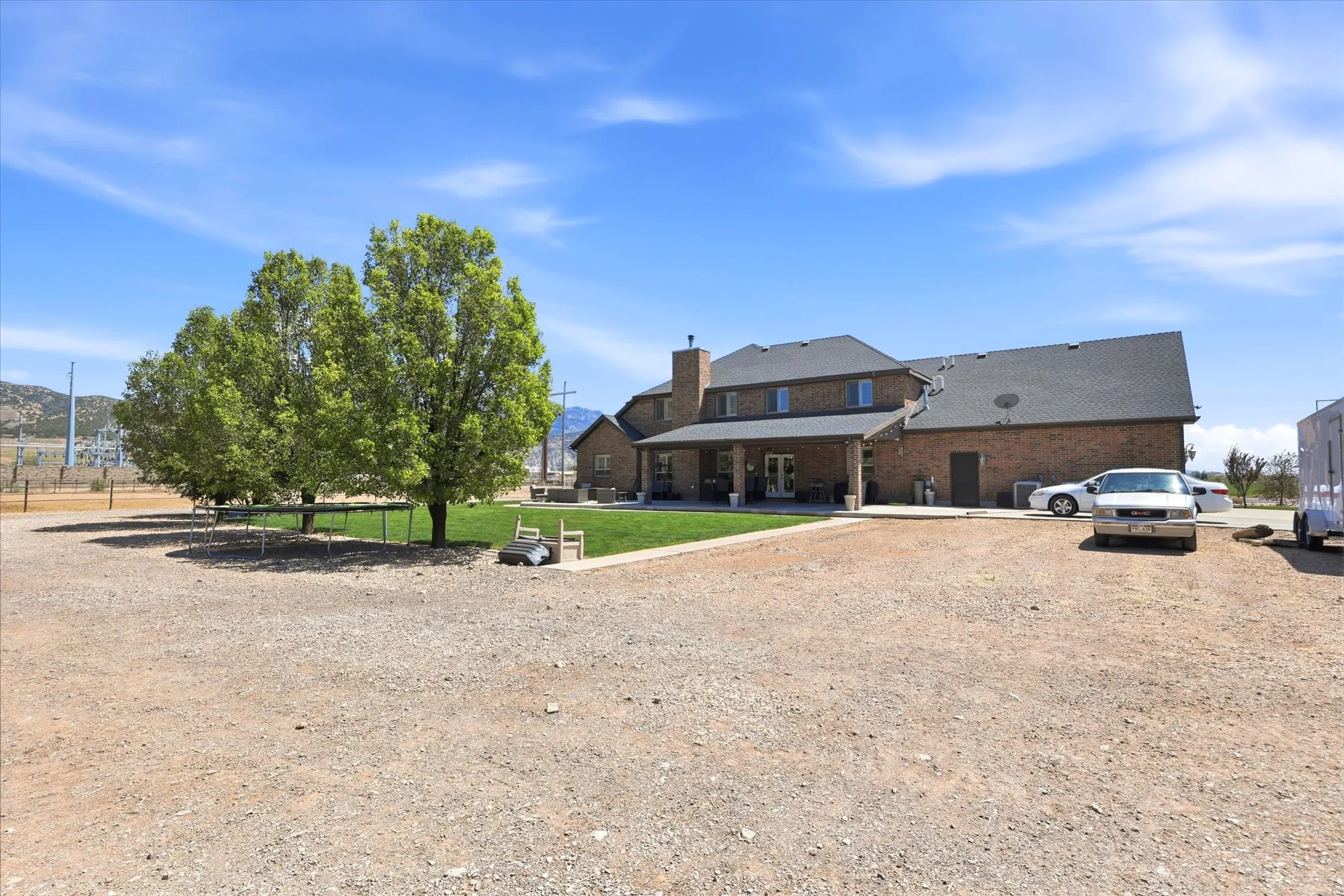 Brick exterior residence featuring a covered patio, a dark shingle roof, and multiple windows