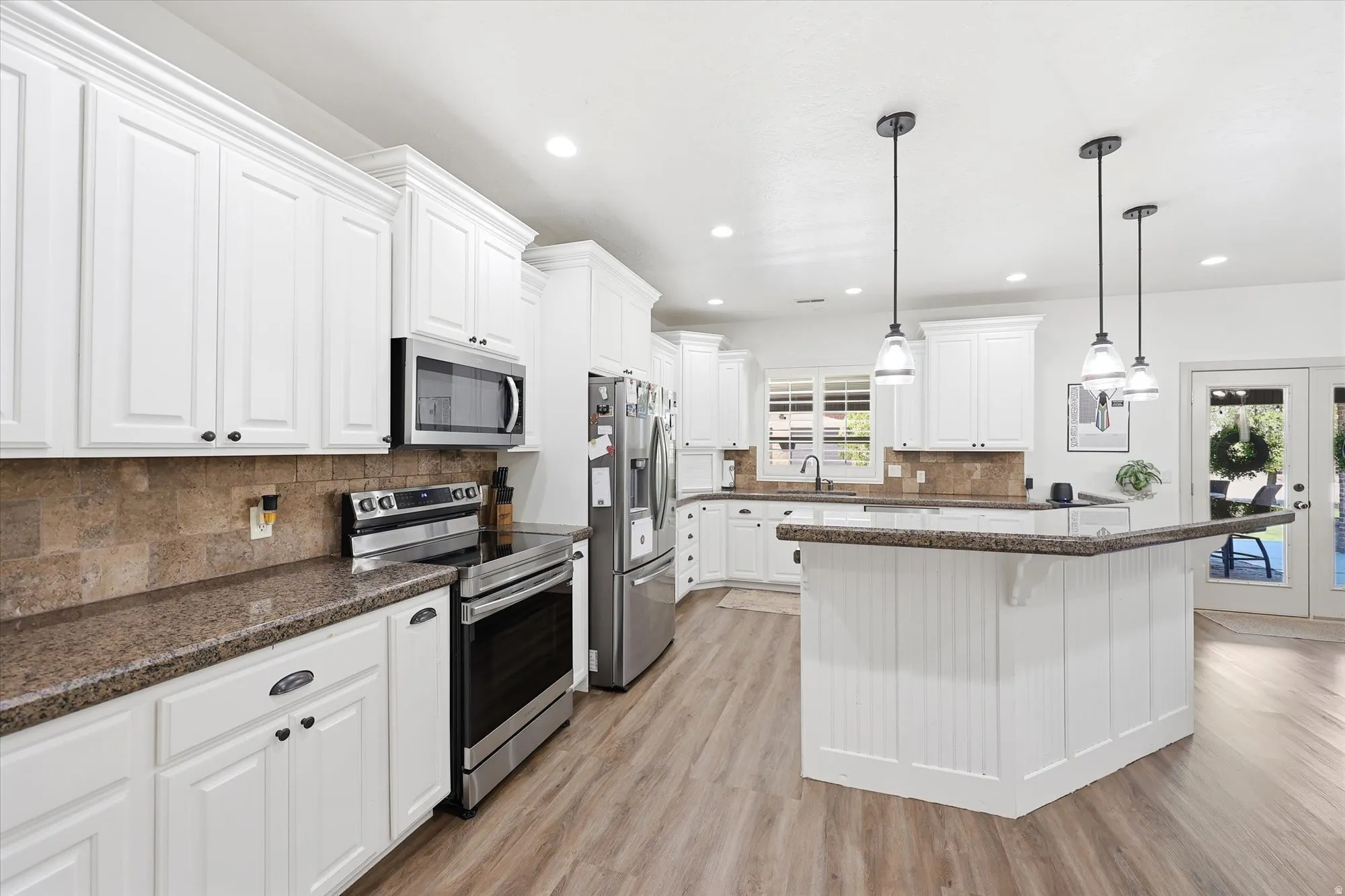 Kitchen featuring white cabinetry, stone-finish countertops, stainless steel appliances, a tiled backsplash, and wood-finish flooring