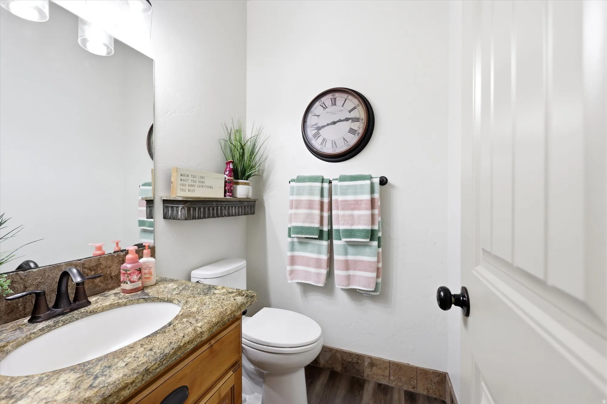Bathroom featuring a vanity with an oval undermount sink, a granite-finish countertop, and a bronze-finish faucet