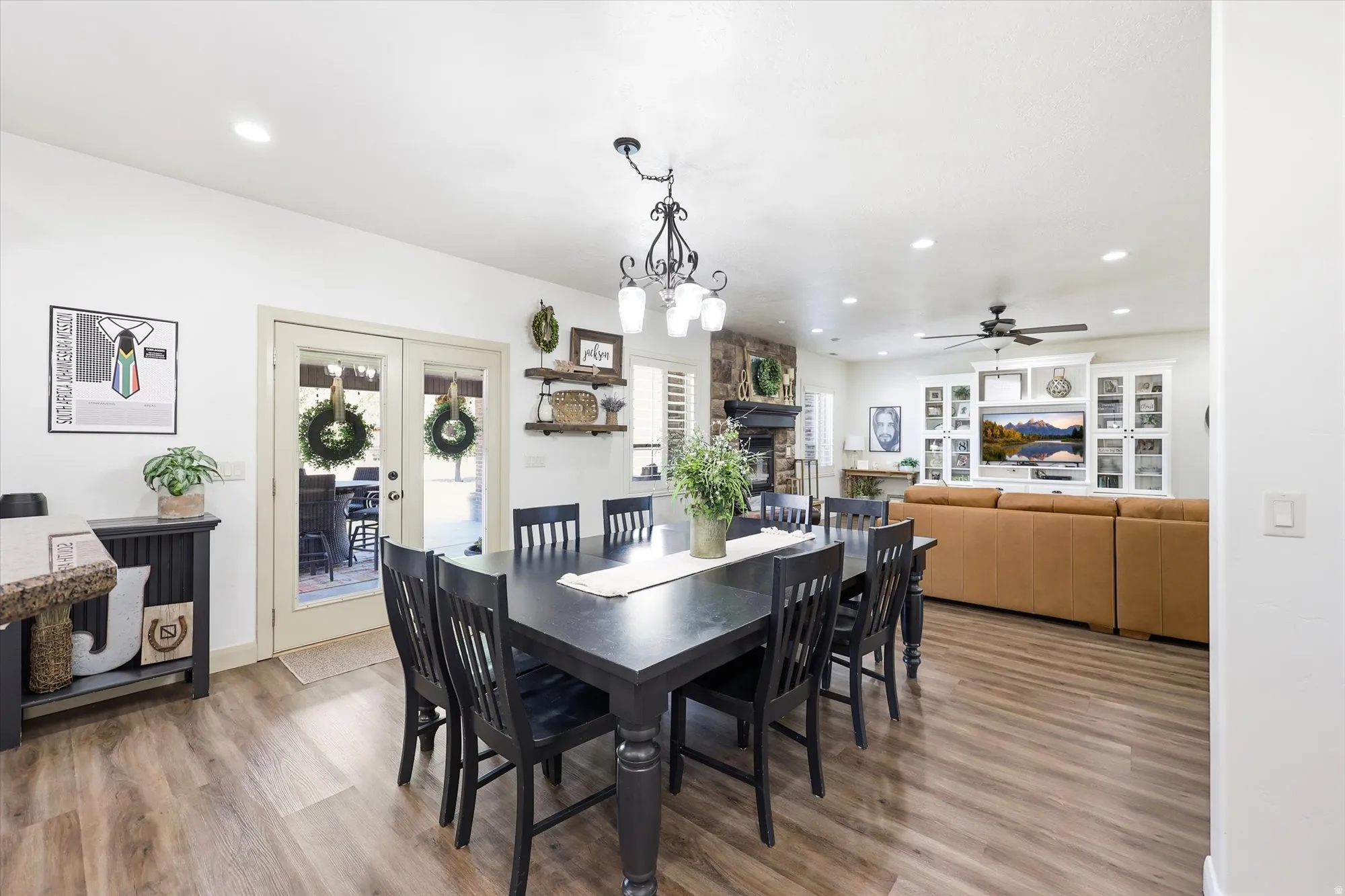Open-concept interior featuring wood-finish flooring, a stone fireplace, recessed lighting, and a ceiling fan