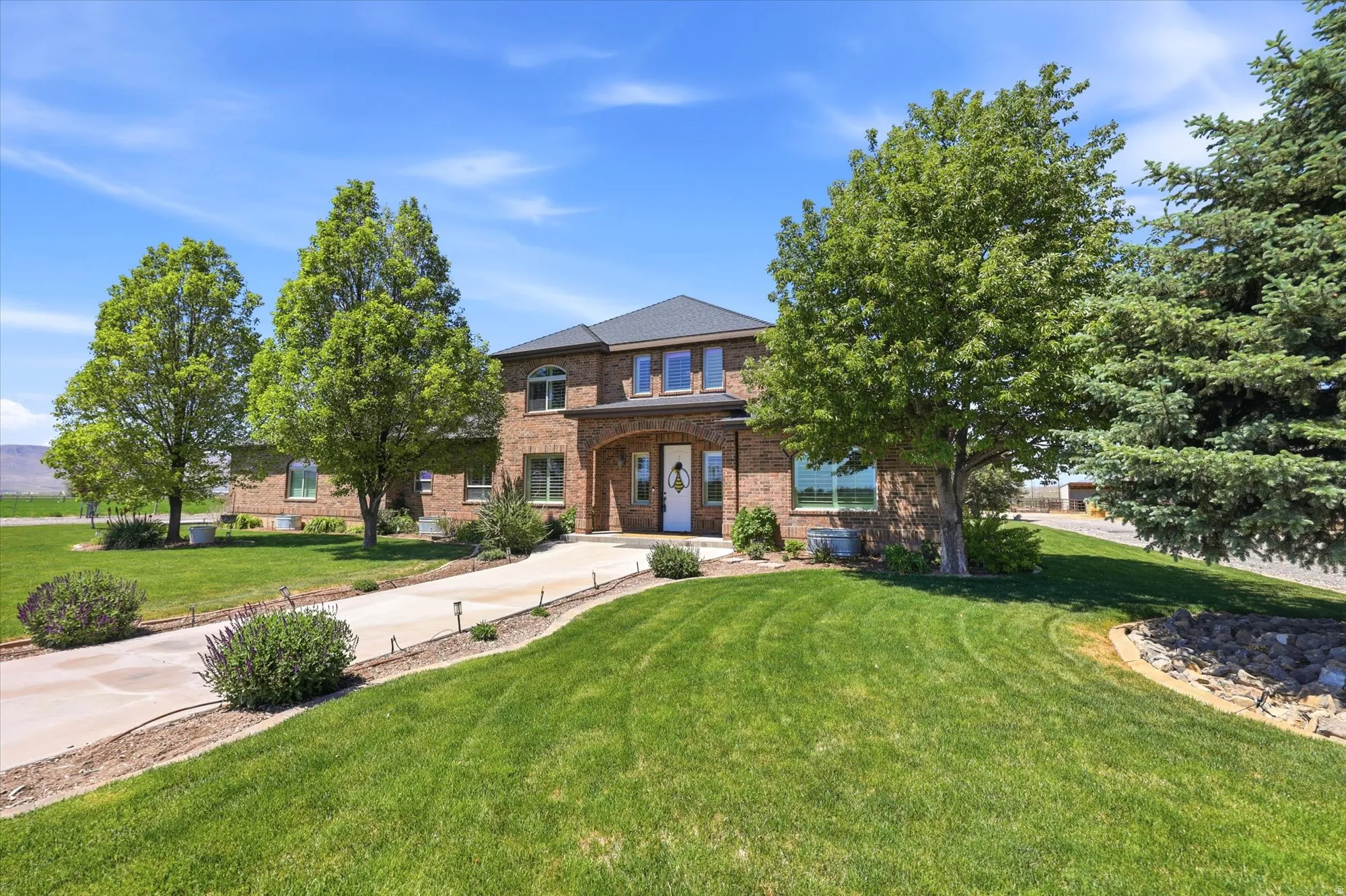 Brick exterior residence featuring a covered entry, arched window above, and a dark shingle roof