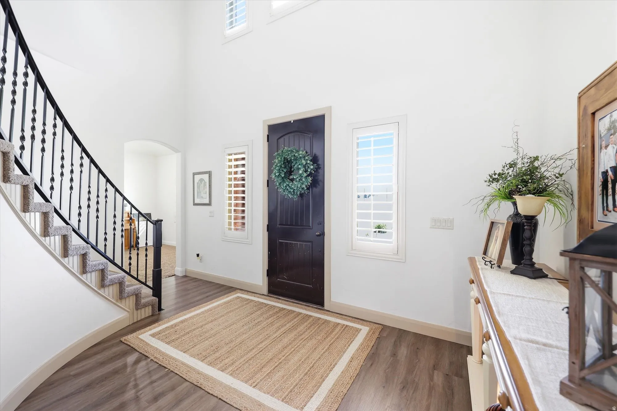 Grand entryway featuring a dark wood-finish door, arched doorways, and soaring ceilings