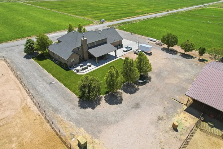 Expansive property featuring a brick exterior residence with a covered patio, a detached barn, and substantial gravel parking areas