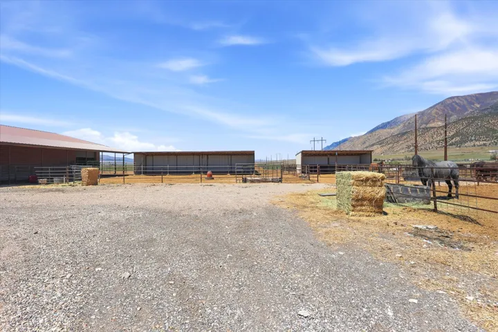 Expansive gravel lot featuring two large covered structures and extensive metal fencing