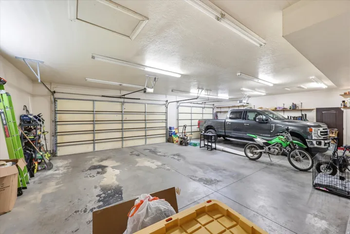 Spacious garage featuring a concrete floor, two overhead doors, and ample overhead lighting