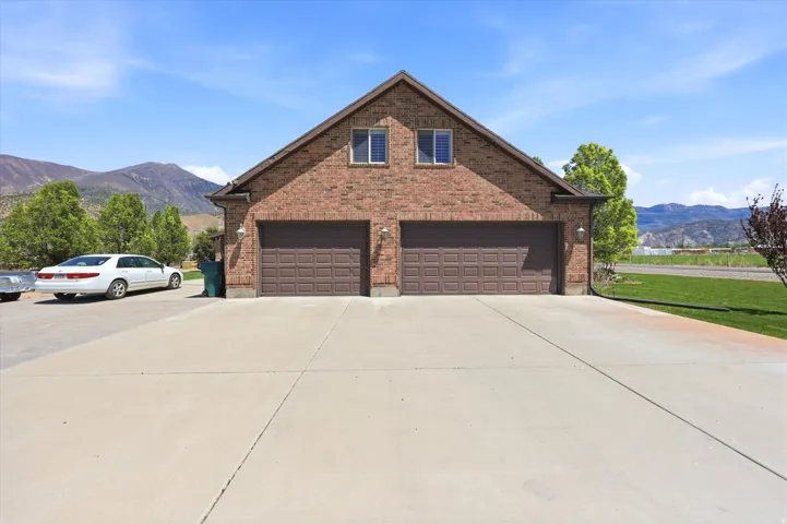 Brick exterior featuring a two-car garage with paneled doors, dual windows on the upper level, and a concrete driveway