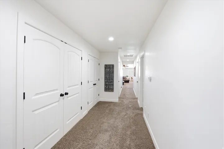 Hallway featuring recessed lighting, light-toned carpeting, white walls, and multiple white doors with black hardware