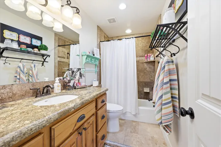 Attached Bathroom - Second Primary Bathroom featuring a single basin vanity with stone countertop, wood cabinetry, and bronze-finish hardware