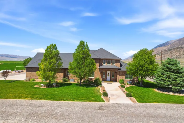 Brick two-story residence featuring a dark shingle roof, a two-car garage, and a concrete driveway