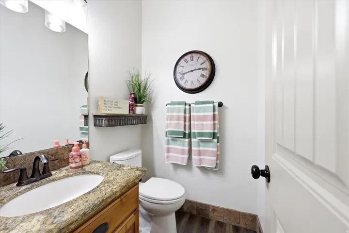 Bathroom featuring a vanity with an oval undermount sink, a granite-finish countertop, and a bronze-finish faucet