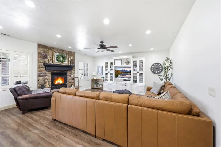 Living area featuring a stone-clad fireplace with a dark mantel, wood-finish flooring, and recessed lighting