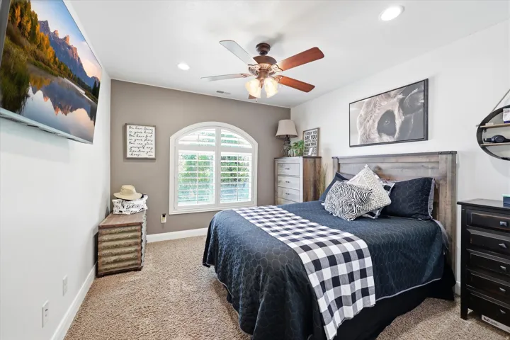 Arched window with plantation shutters, recessed lighting, and a ceiling fan