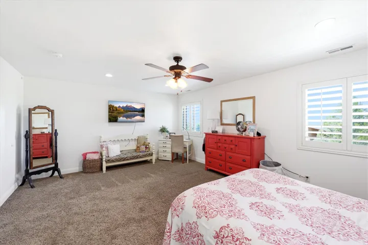 Second Primary Spacious room featuring neutral carpeting, white walls, and multiple windows with white plantation shutters