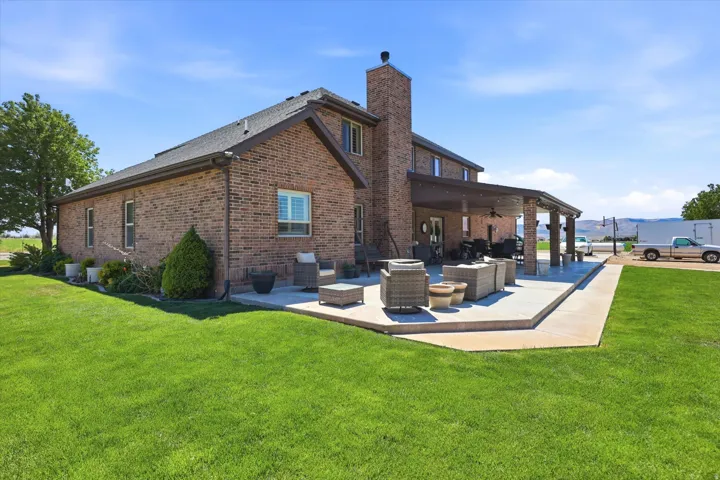 Expansive rear patio featuring a covered outdoor living area and a brick exterior with a prominent chimney