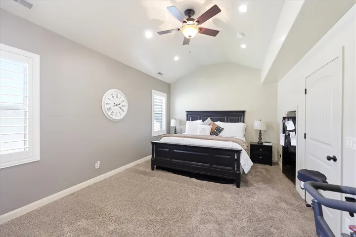 PRIMARY Spacious room featuring vaulted ceilings, recessed lighting, a ceiling fan with light fixture, plantation shutters, and soft carpet flooring
