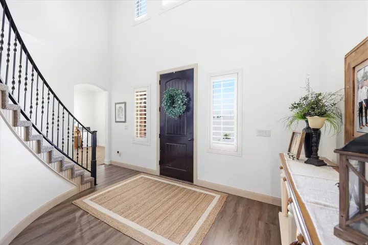 Grand entryway featuring a dark wood-finish door, arched doorways, and soaring ceilings