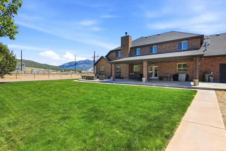Expansive green lawn with a covered patio spanning the rear of the brick-clad residence
