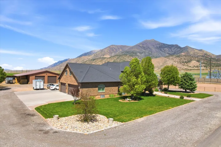 Brick facade residence featuring an attached double-door garage, expansive paved driveway, and established lawn landscaping