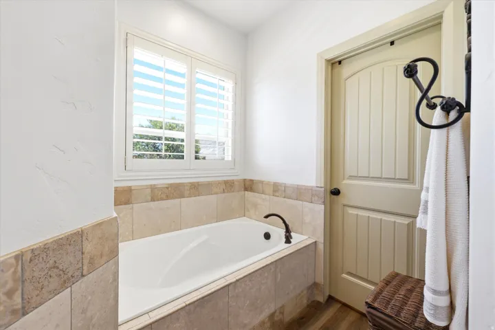 PRIMARY Soaking tub with a bronze-finish faucet, surrounded by natural stone tile