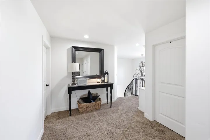 Carpeted hallway featuring bright white walls and recessed lighting