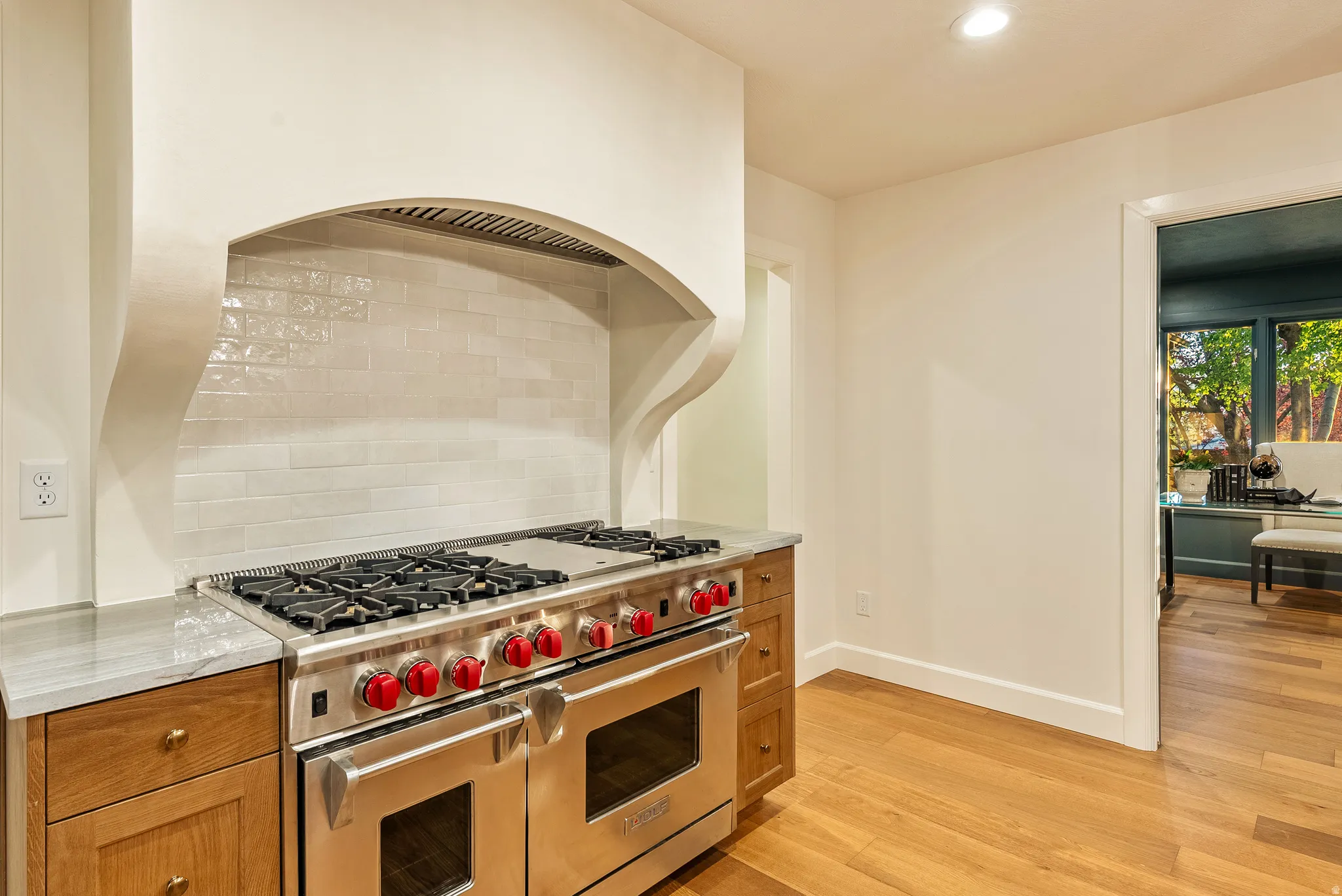 Stainless steel professional-grade range with red accents, integrated beneath a custom-designed range hood