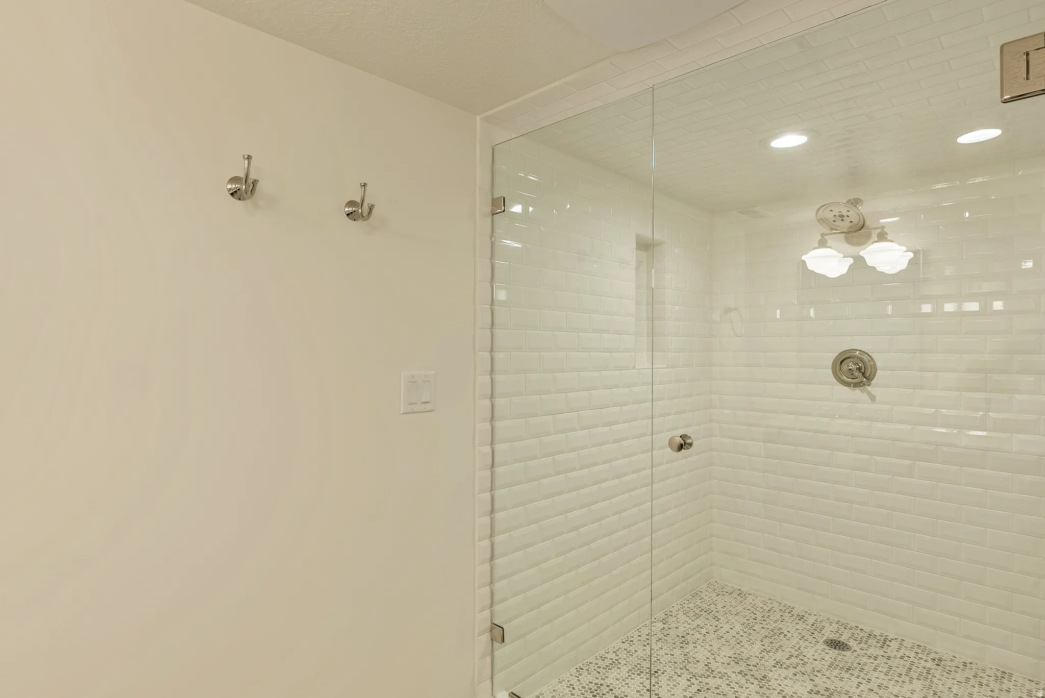 Glass-enclosed shower with white subway tile walls, a mosaic tile floor, and brushed nickel fixtures